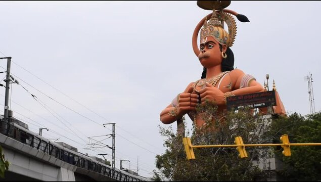 Delhi metro train passing near big statue of Lord Hanuman situated near Karol Bagh, Delhi, India, Lord Hanuman big statue touching sky