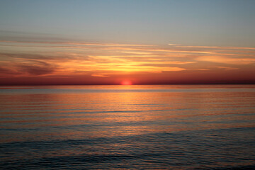 Fototapeta na wymiar Sunsetting sky above calm sea during the dusk. Selective focus