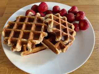 Belgian waffle made from banana dressed on a white plate with fresh red strawberries. Selective focus