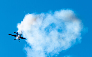 Silhouettes of training aircraft performing aerobatics on a clear sunny day.