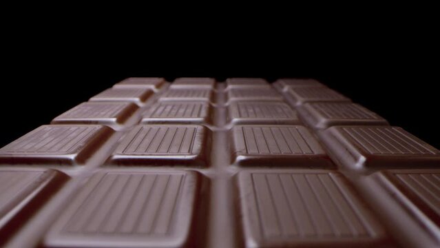 Macro Shot Of Long Sweet Milk Chocolate Bar Isolated On Black Background