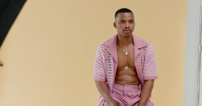 Fashion, photography and male model working at photo shoot for beauty, style and designer clothing. Modelling, pose and trendy black man in professional studio set with yellow backdrop and equipment