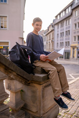 Teenager with a textbook seated on the concrete railing