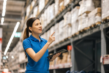 Fototapeta Young female worker in blue uniform checklist manage parcel box product in warehouse. Asian woman employee holding tablet working at store industry. Logistic import export concept. obraz