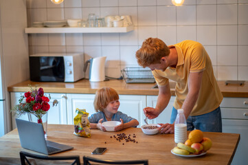 Young father making breakfast for his little son