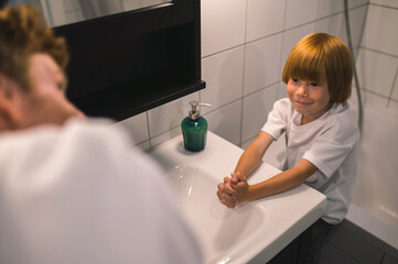 Cute little boy and his dad washing hands in the bathroom