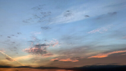 Sunset in the evening sky. An almost clear light blue sky with rare clouds of bizarre shapes. The...