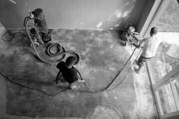 .Construction workers in a family home living room that grind the concrete surface before applying...