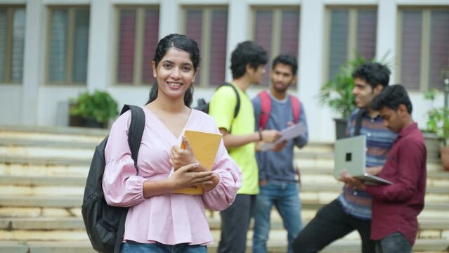 Happy young girl with backpack and books smilling by looking camera at college campus - concept of education, internship and skills development