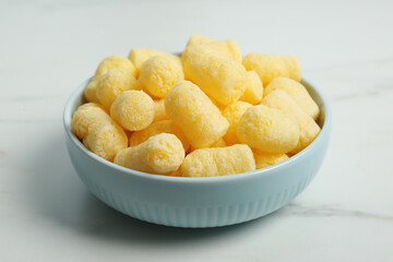 Bowl of delicious crispy corn sticks on white marble table