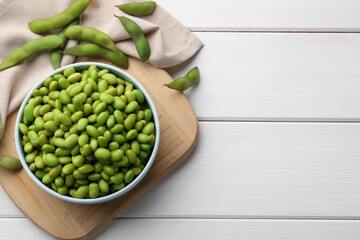 Organic edamame beans on white wooden table, flat lay. Space for text