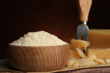 Delicious grated parmesan cheese in bowl on wooden table