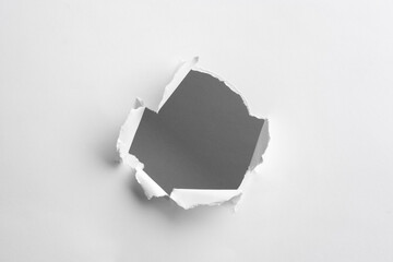 Hole in white paper on light background