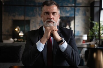 Portrait shot of executive senior businessman wearing suit and tie while sitting at office desk