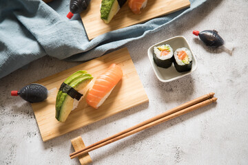 Lachs Avocado Sushi als Nigiri, Maki, roh auf Holz Teller mit Soja Soße in Fisch Verpackung und...