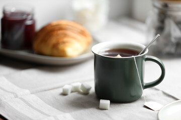 Cup of freshly brewed tea and sugar cubes on table