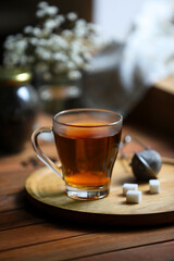 Tray with cup of freshly brewed tea and sugar cubes on wooden table indoors