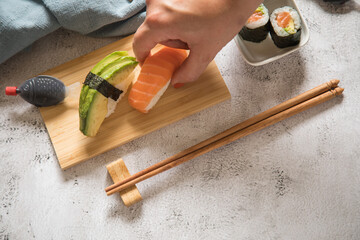 Frau isst Lachs Avocado Sushi als Nigiri, Maki, roh auf Holz Teller mit Soja Soße in Fisch...