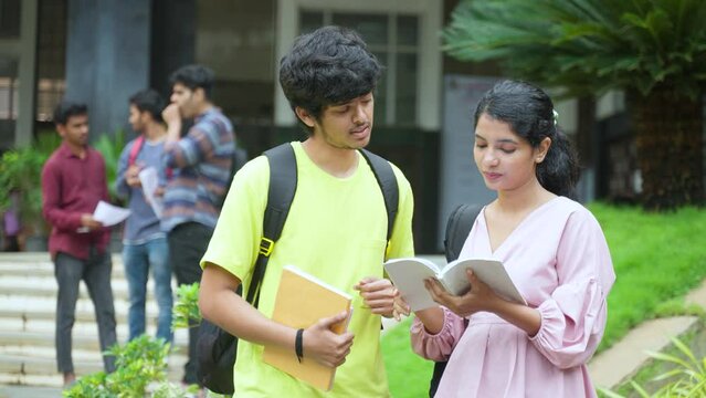Serious college students discussing from books at campus before exams - concept of communication, education and exam preparation