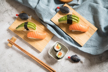 Lachs Avocado Sushi als Nigiri, Maki, roh auf Holz Teller mit Soja Soße in Fisch Verpackung und...