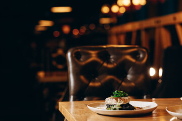 Baked fish on a rice pillow with cuttlefish ink, garnished with seaweed and papaya sauce.