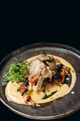 Baked meat with mushroom sauce and fresh mushrooms. On a black background.