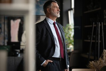 Success concept. Stylish bearded man in a suit standing in modern office.