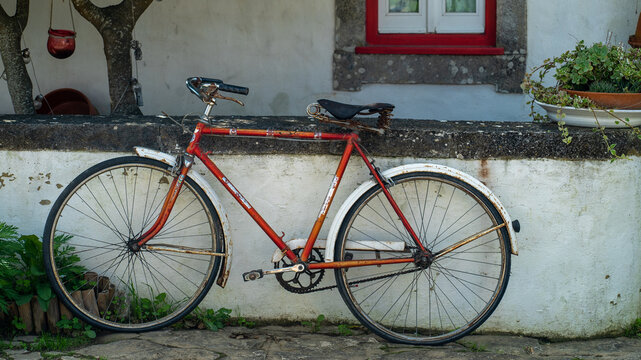bicicleta vermelha encostada a um muro de uma casa antiga