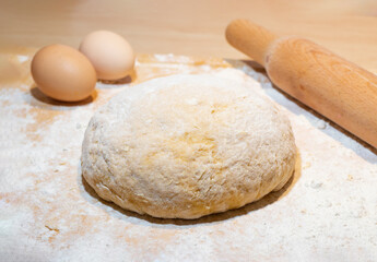 Fototapeta na wymiar Fresh dough for pasta on a wooden surface. With two eggs. Kneaded by hand
