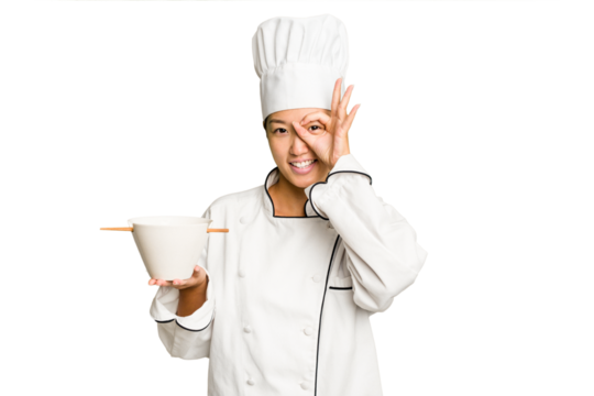 Young chef asian woman holding a bowl of ramen isolated excited keeping ok gesture on eye.