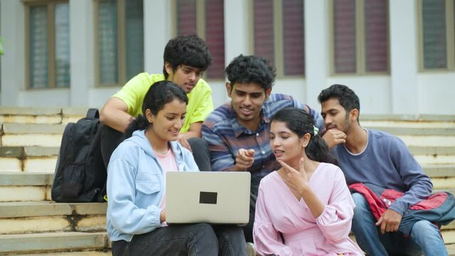 Group of students checking results on laptop while sitting on college campus - concept of education, teamwork and project work discussion.