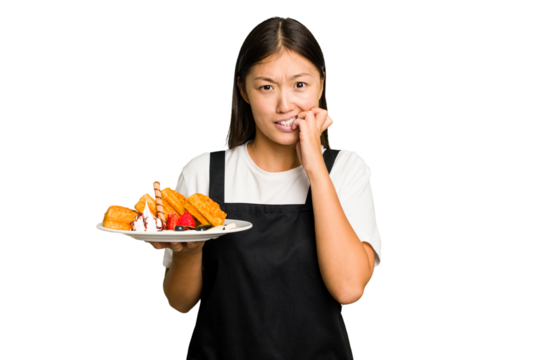 Young asian waitress woman holding waffles isolated biting fingernails, nervous and very anxious.