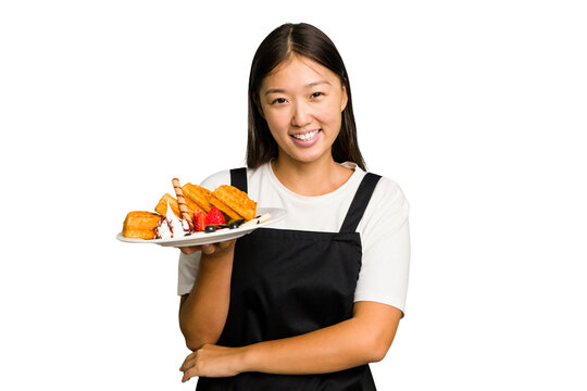 Young asian waitress woman holding waffles isolated laughing and having fun.