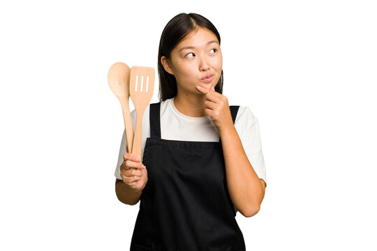 Young asian cook woman isolated looking sideways with doubtful and skeptical expression.