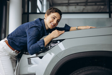 Woman hugging a new car in a car showroom