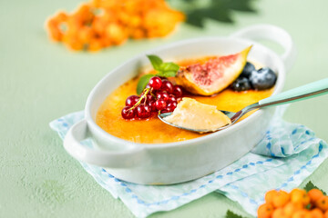 Recipe for Creme brulee dessert with fresh figs, blueberries and currants on a green stone table in autumn composition.