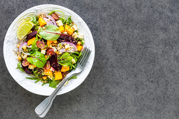 Fresh vegetable salad with beetroot, arugula, red onion, sorrel, chickpeas, pumpkin and grapes in a...