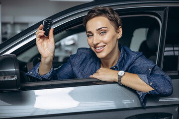 Woman holding car keys and sniling sitting in car