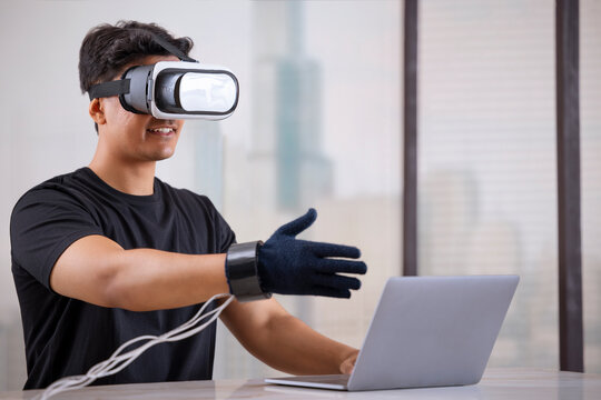 Man wearing VR headset and haptic glove interacting with virtual object/person in the metaverse