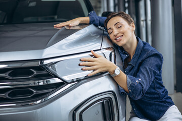 Woman hugging a new car in a car showroom