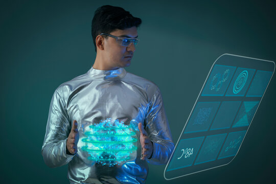 A man wearing silver, futuristic  clothes holding digital globe, and looking at a digital screen. A future technology concept