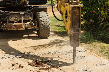 An excavator fitted with a hydraulic breaker destroying a portion of a damaged street. Road...