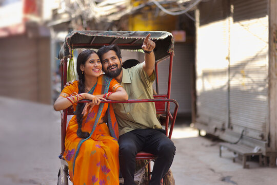 Portrait of happy young couple riding rickshaw together on the road