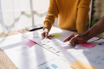 A UX design team is a confluence of user research, UX, UI design with layout paper on desk.