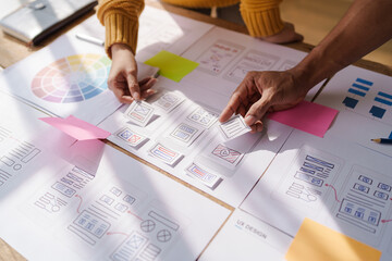 A UX design team is a confluence of user research, UX, UI design with layout paper on desk.