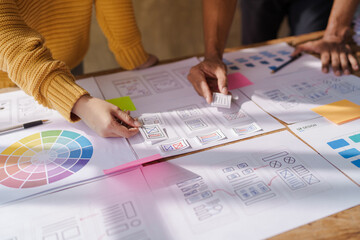 A UX design team is a confluence of user research, UX, UI design with layout paper on desk.