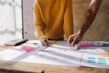 A UX design team is a confluence of user research, UX, UI design with layout paper on desk.