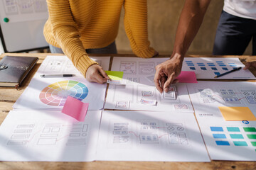 A UX design team is a confluence of user research, UX, UI design with layout paper on desk.