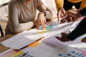 A UX design team is a confluence of user research, UX, UI design with layout paper on desk.