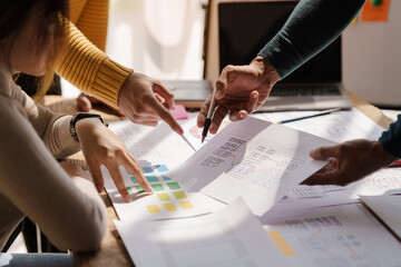 A UX design team is a confluence of user research, UX, UI design with layout paper on desk.